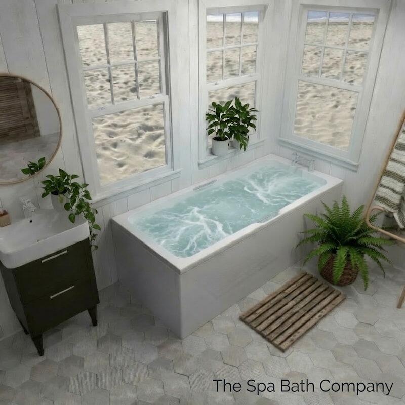 A luxury white whirpool bath surround by plants with a view of the beach through the window
