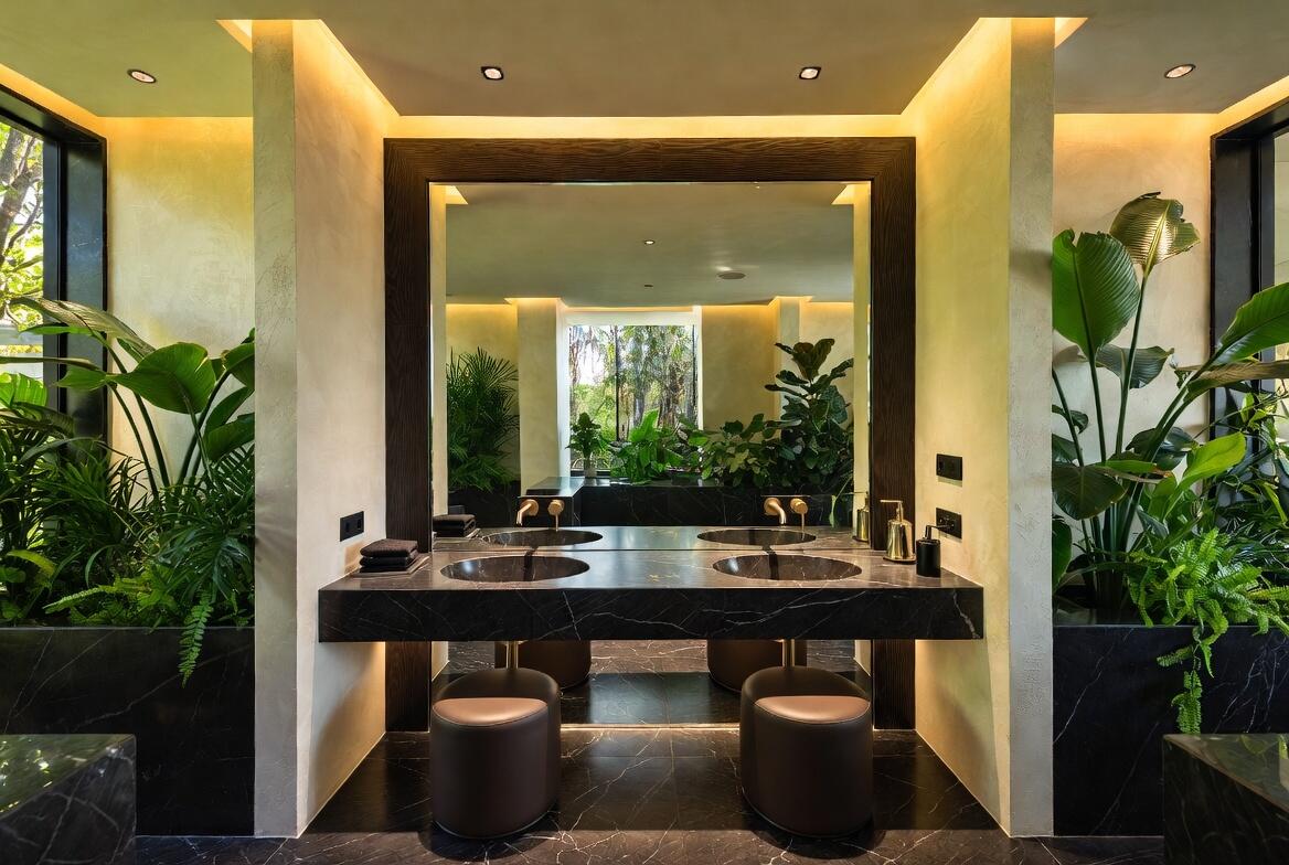 Luxurious double vanity bathroom with stone finishes and abundant greenery