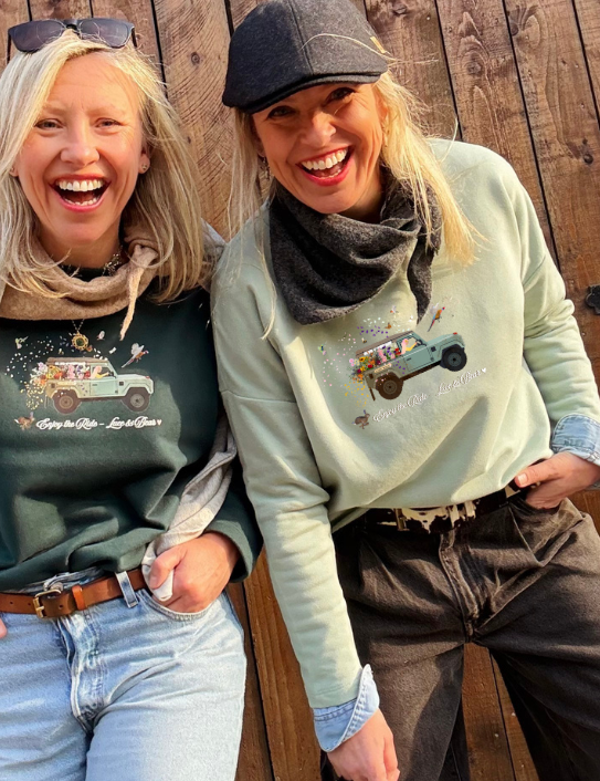 Two women wearing Enjoy the Ride sweatshirts