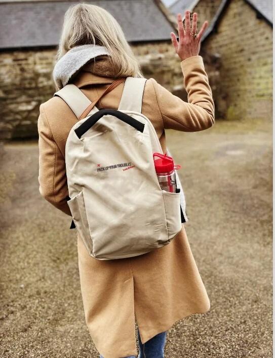 Woman walking away with stone coloured Pack Up Yer Troubles Backpack