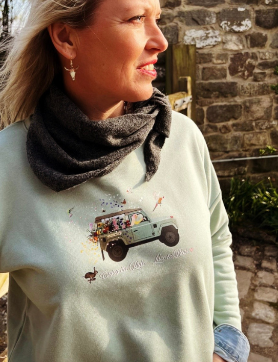 Woman wearing dusty green Enjoy the Ride sweatshirt