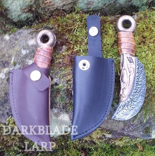 A throwing knife with a curved edge inside a fitted scabbard. There is an unsheathed knife and an empty scabbard next to it