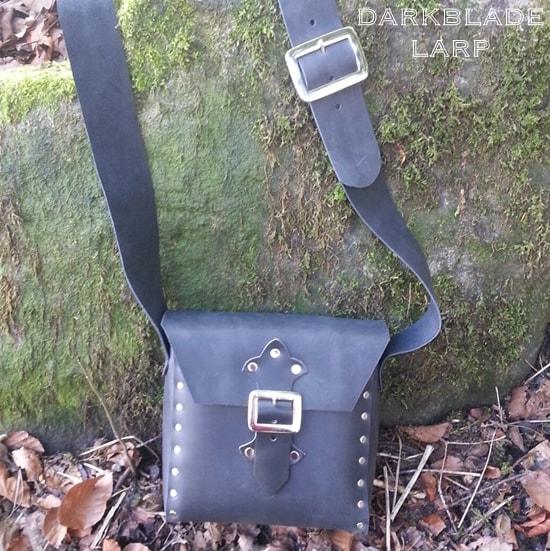 Small leather satchel with strap and buckle closure.