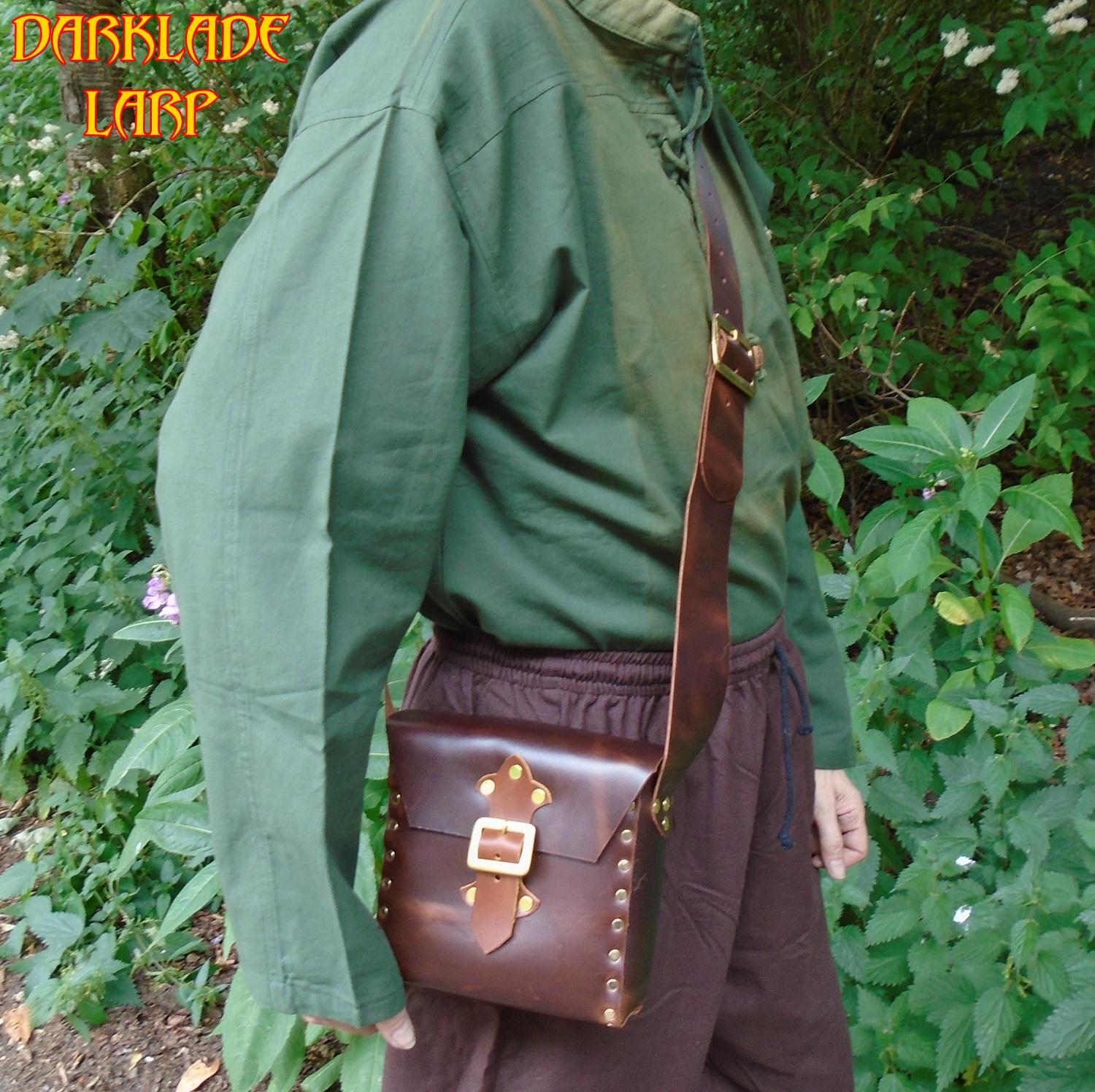 small leather satchel with a buckle closure being worn across the body