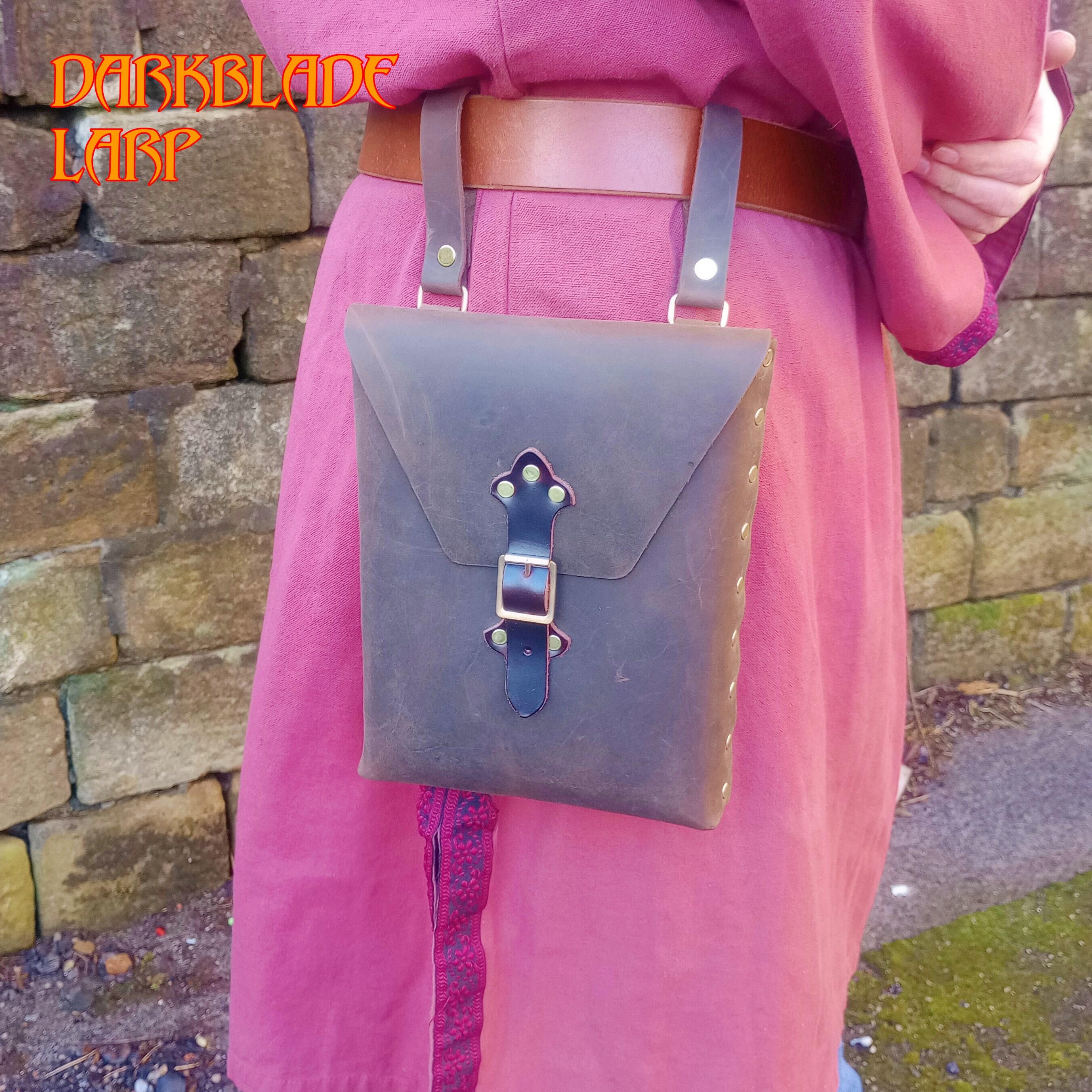 A brown leather pouch, quite flat, about A5 size fastened with a strap and buckle set on a flap coming down about halfway down the length of the poucha