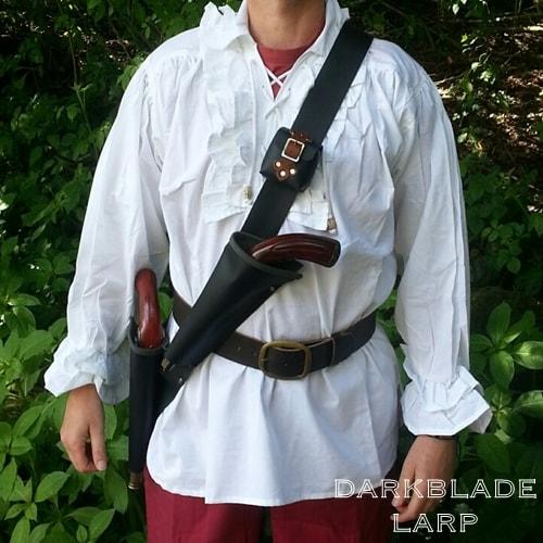 A baldric-style strap with two gun holsters, one on the hip and the second just above the waist. There is a small pouch about halfway up the strap at the front.