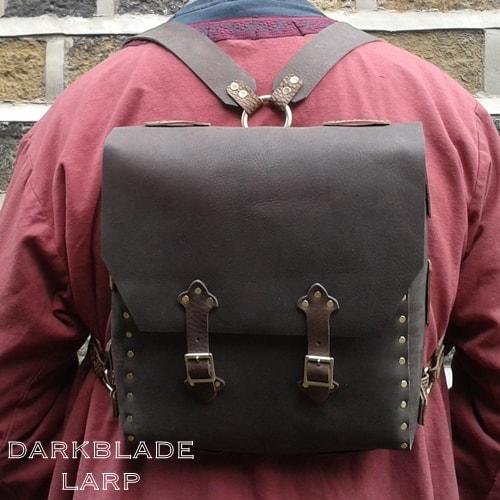 A leather knapsack with both shoulder straps attached to a ring in the middle of the back edge