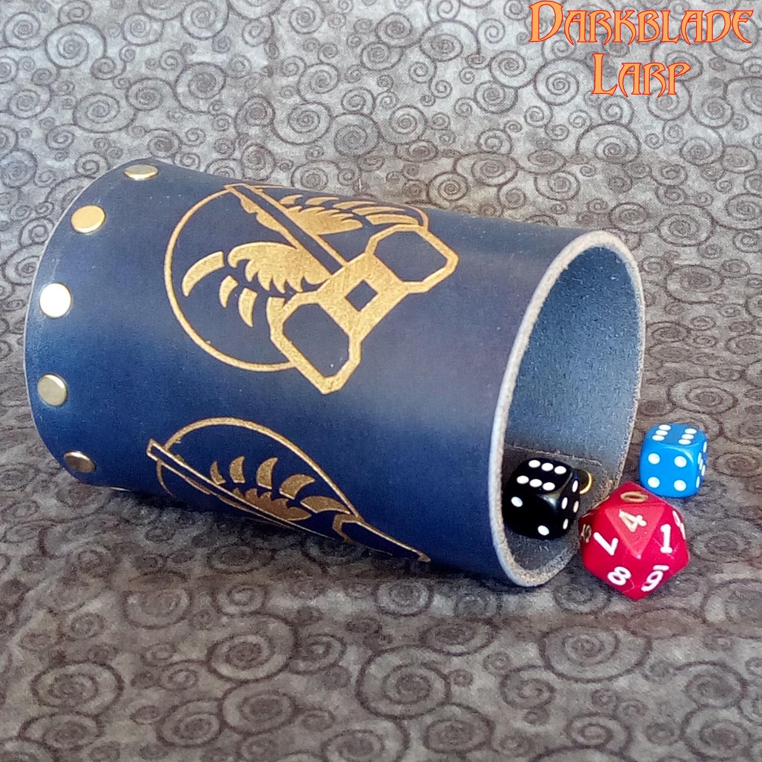 A blue cup with a clericsal symbol engraved on it lying on its side. There are dice rolling out of it.