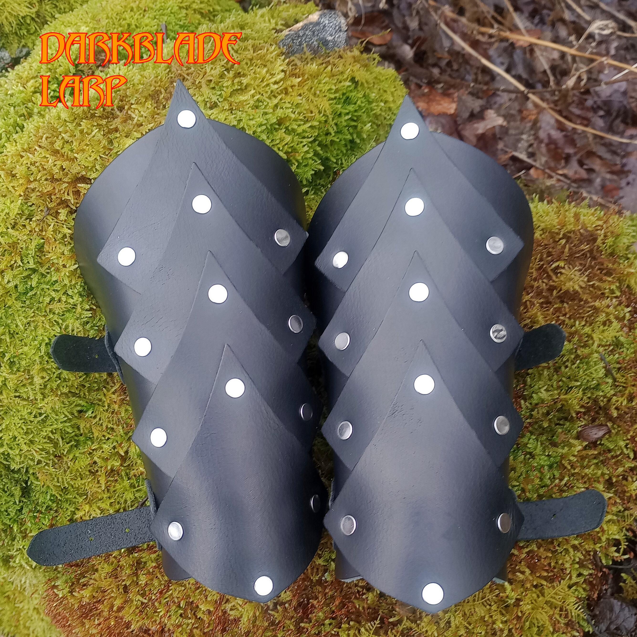 A pair of black vambraces with what looks like a line of scales going down the middle