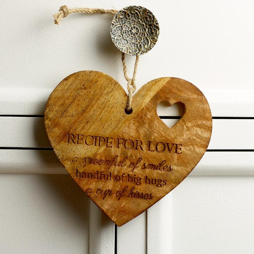 wooden hanging heart decoration with the words "Recipe for Love: A spoonful of smiles, a handful of big hugs, and a cup of kisses" hanging from draw handle