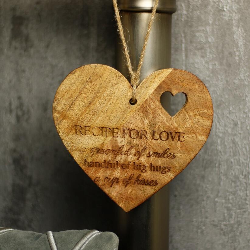 wooden hanging heart decoration with the words "Recipe for Love: A spoonful of smiles, a handful of big hugs, and a cup of kisses" hanging from bedpost