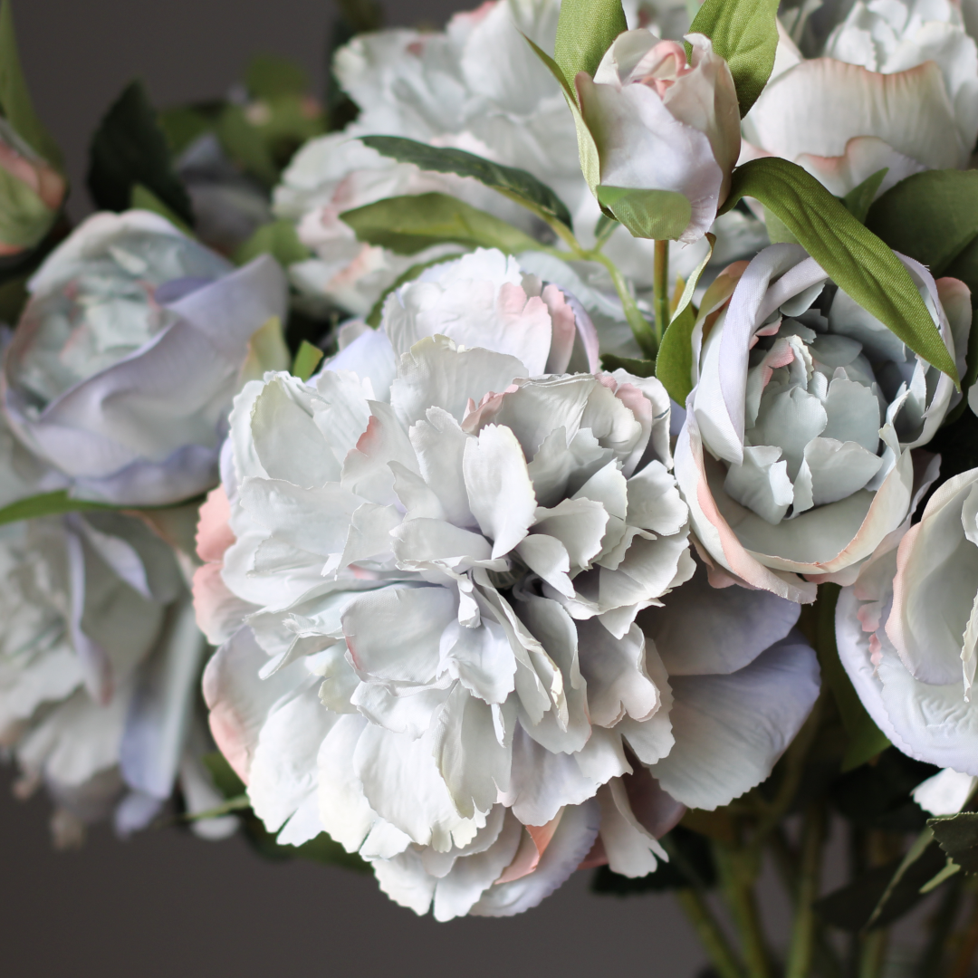 close-up of realistic dusty blue peony flowers made from silk with soft pink edges