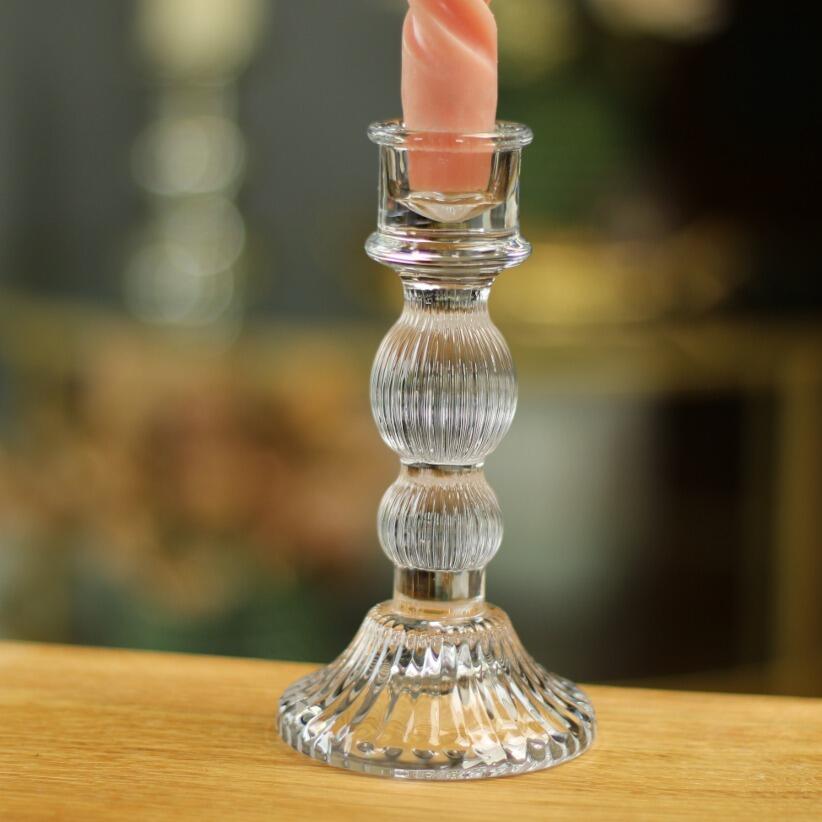 clear glass taper candle holder with pink taper candle on wooden tops