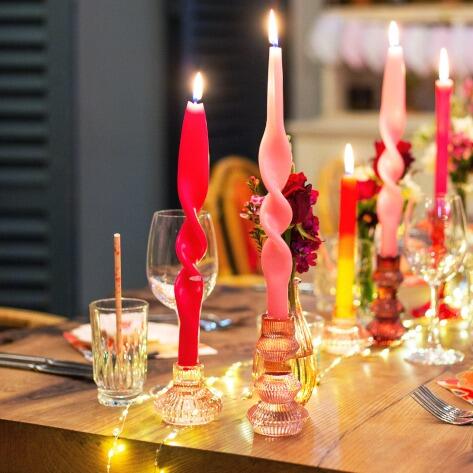 Glass candle holders flickering on a set wooden dinner table