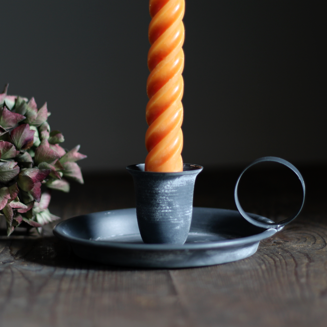 metal chamberstick with a bright orange twisted taper candle