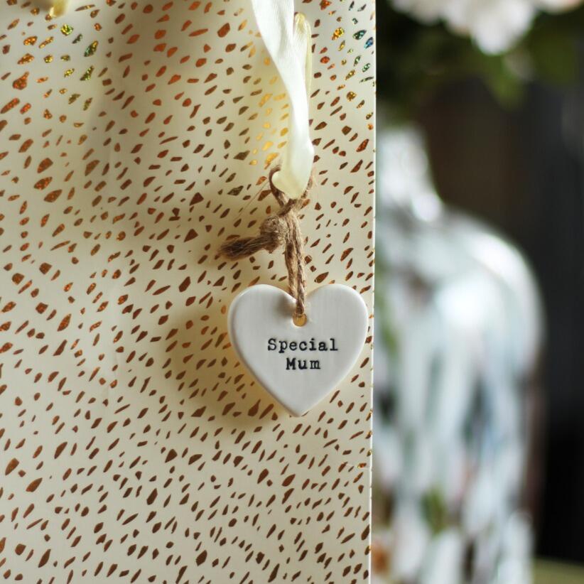White ceramic heart shaped hanging decoration with the words special mum hanging from gift bag