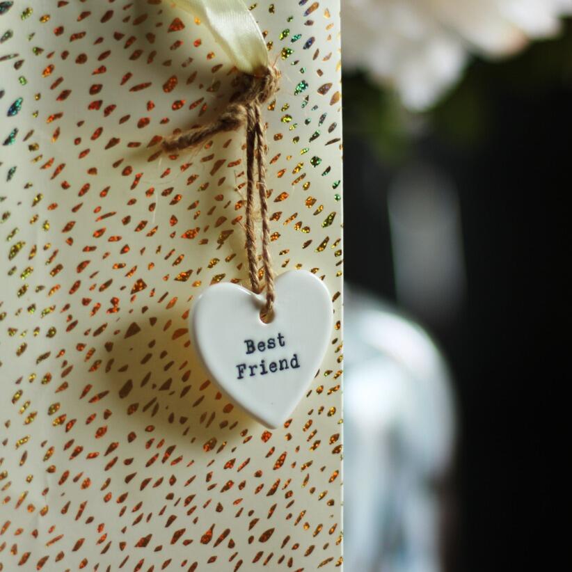 Small ceramic hanging heart with the words best friend hanging from gift bag