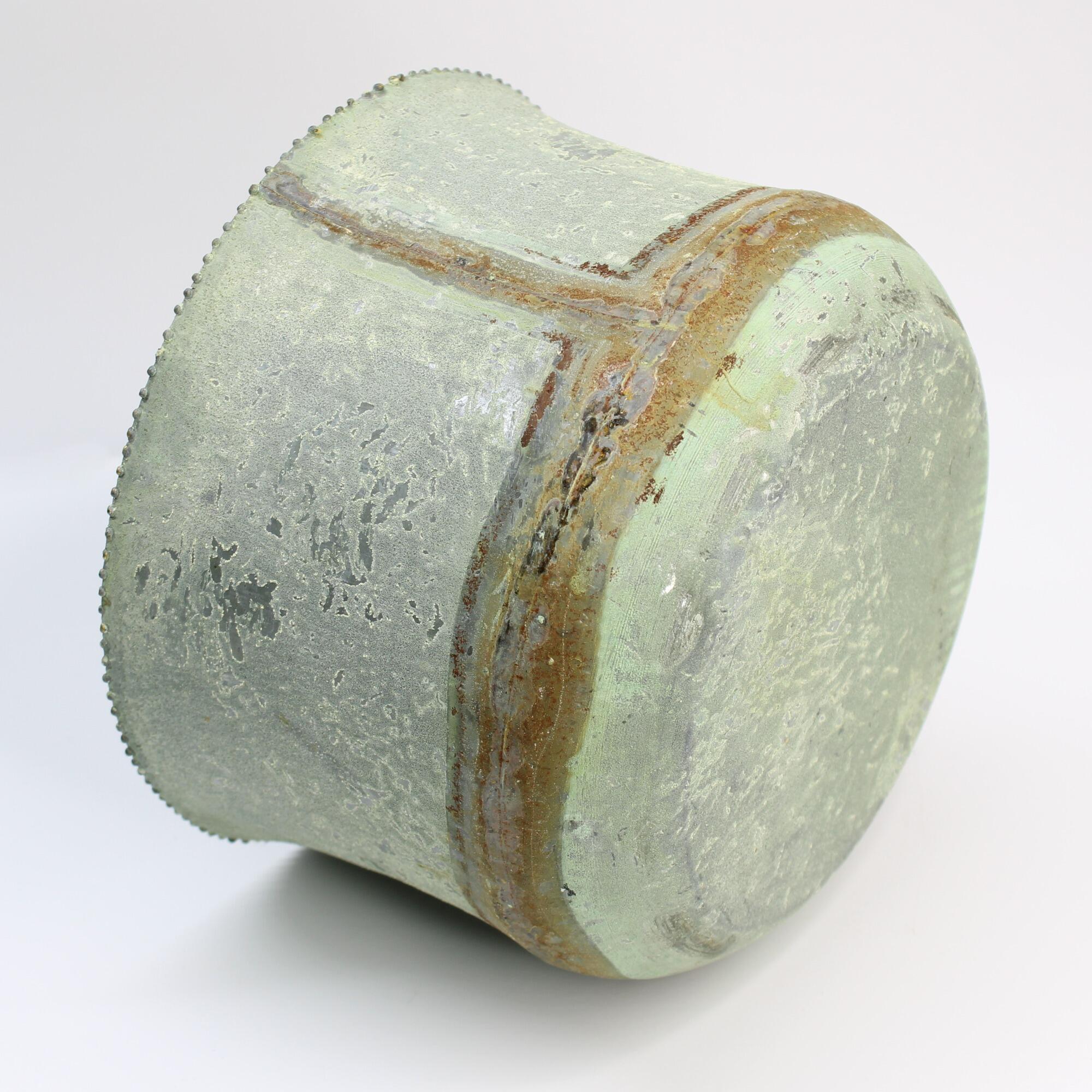 Distressed shabby chic cachepot, bottom angled view of green oxidized metal with a heavy patina.