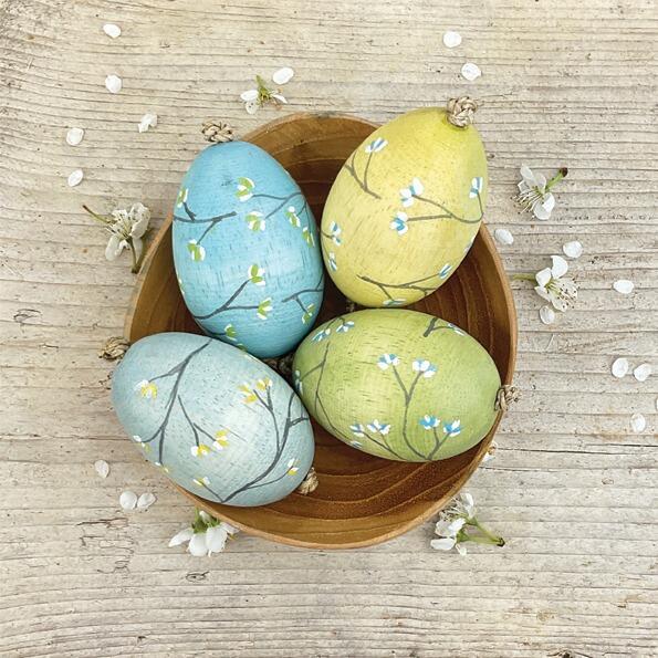 Four colorful eggs in a bowl in a rustic wooden bowl.