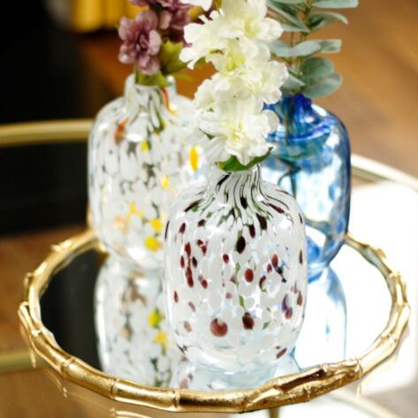 Three speckled flower vases on a glass coffee table