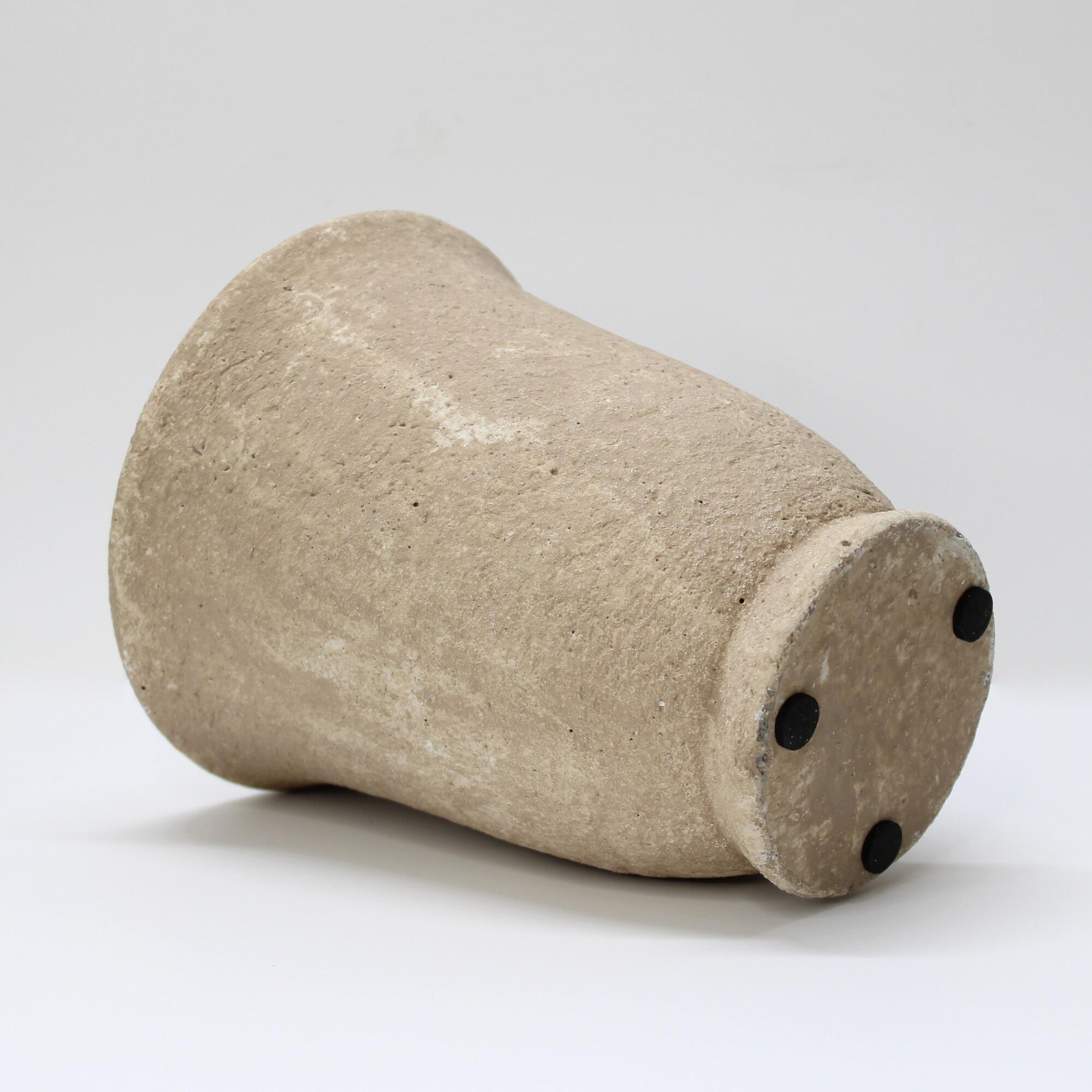 Coarse weathered textured urn pot on its side focusing on the pedestal base.