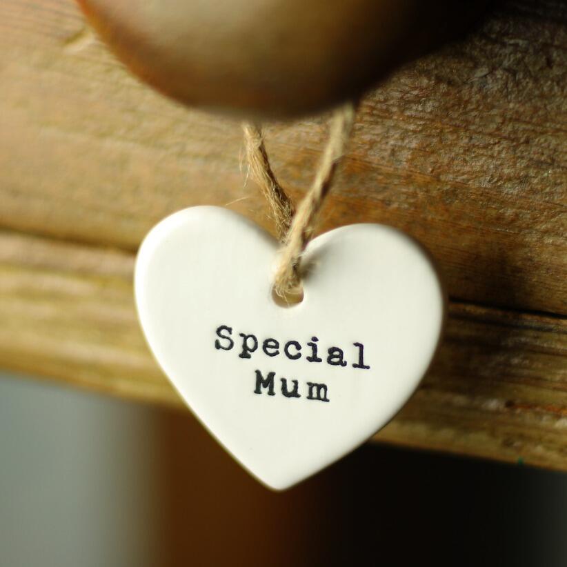 White ceramic heart shaped hanging decoration with the words special mum elegantly written on it hanging from old pine drawer handle