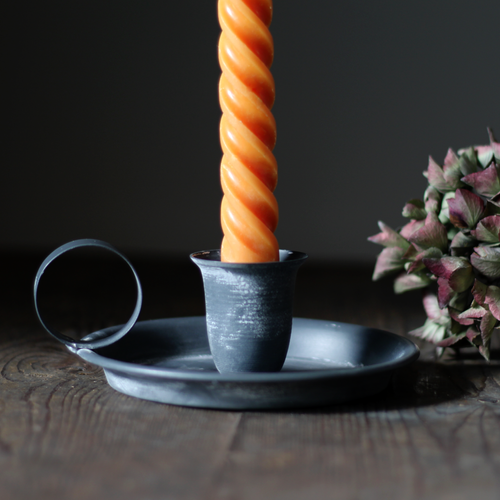 vintage-style metal chamberstick with a bright orange twisted taper candle