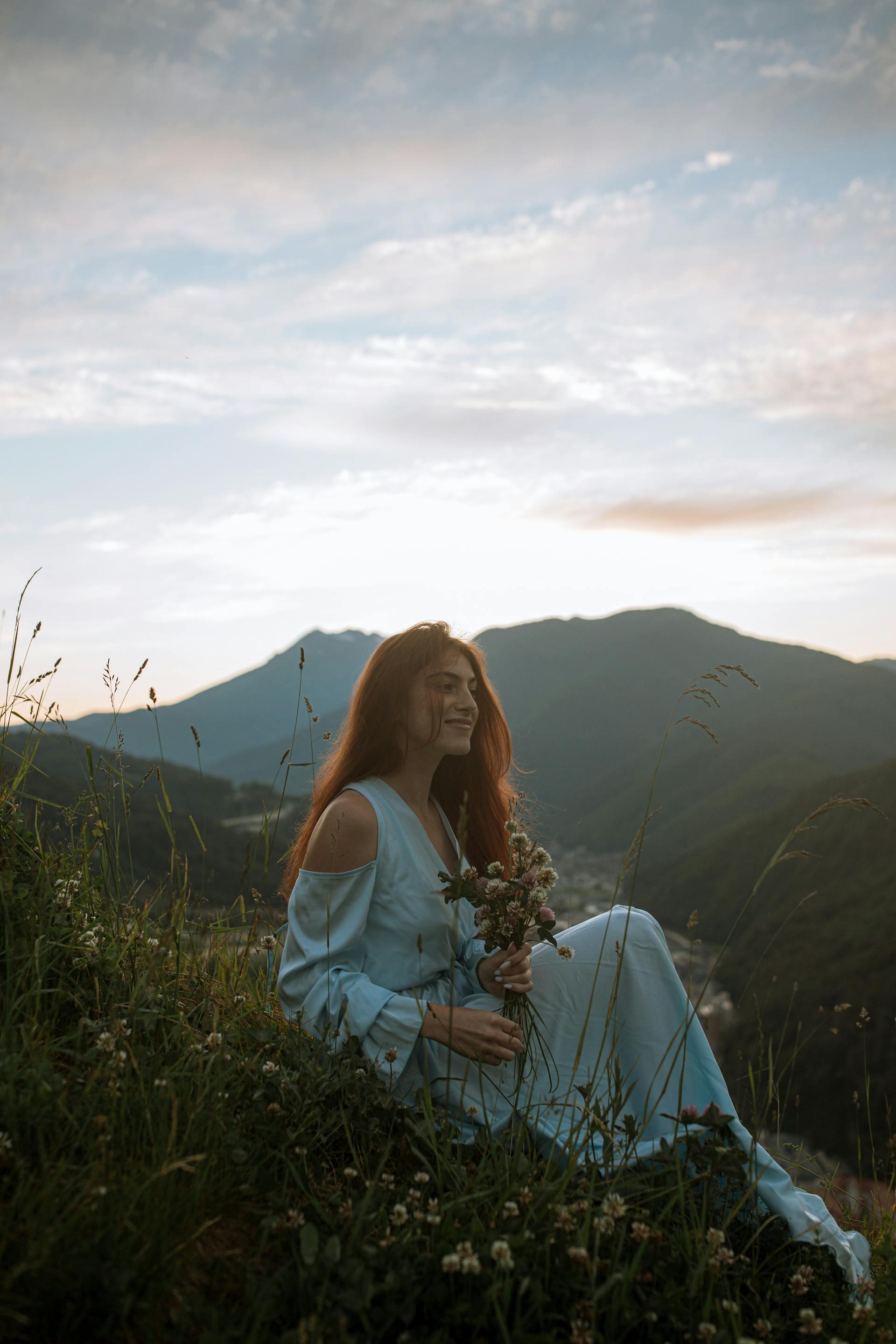 A woman sitting on the earth with flowers around here and grounding