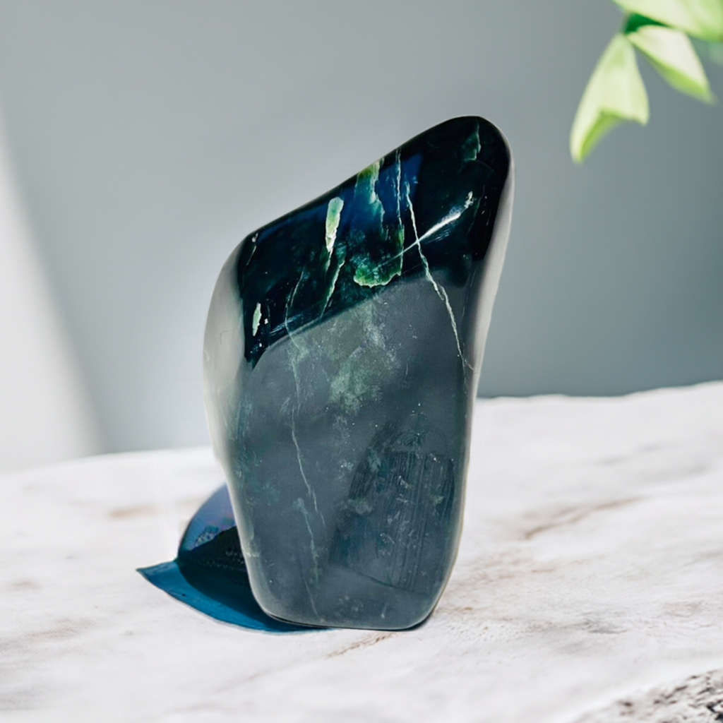 Nephrite free form crystal on a table with a green leaf