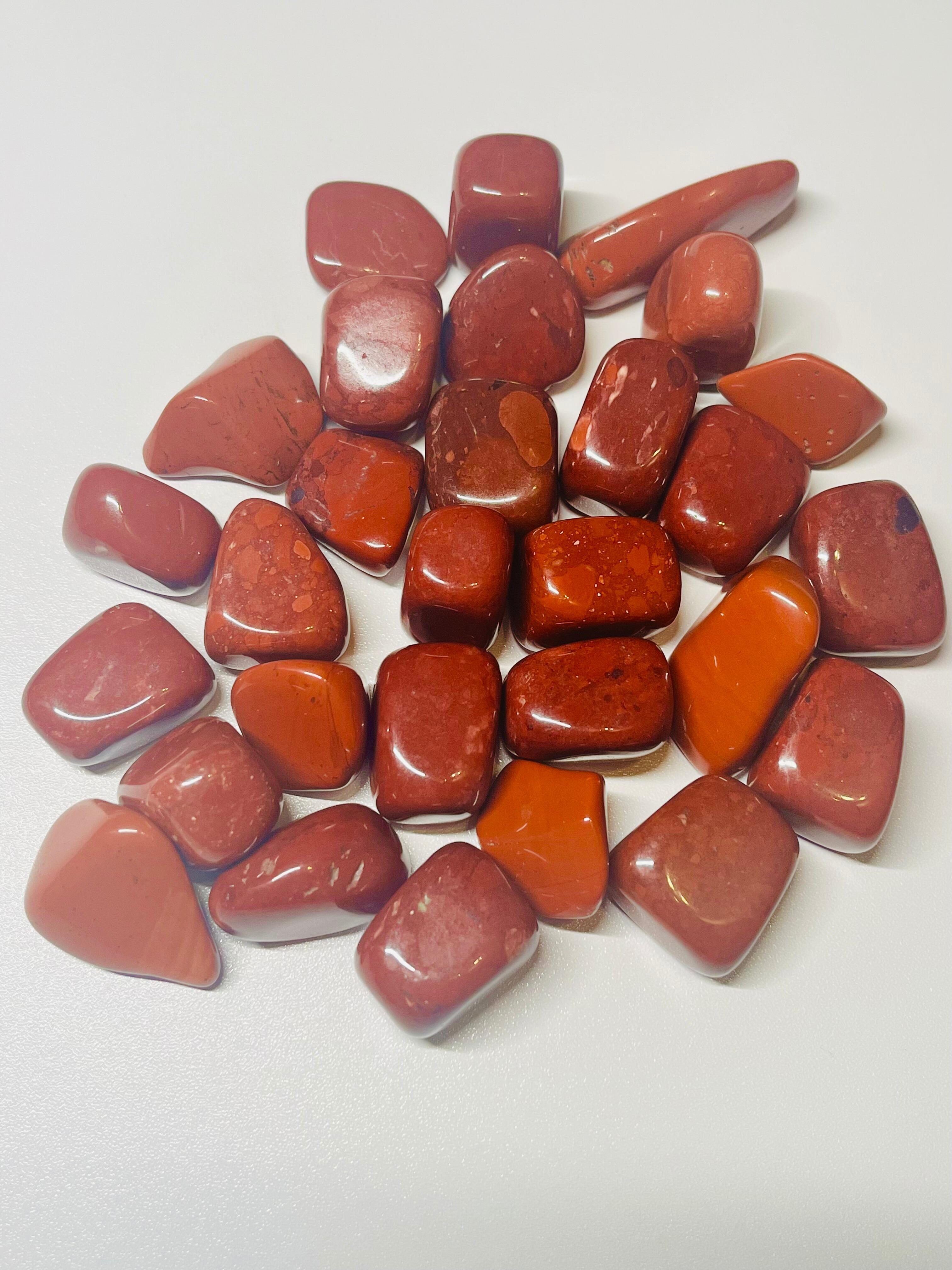 Many Red Jasper tumblestone healing crystals scattered on a table