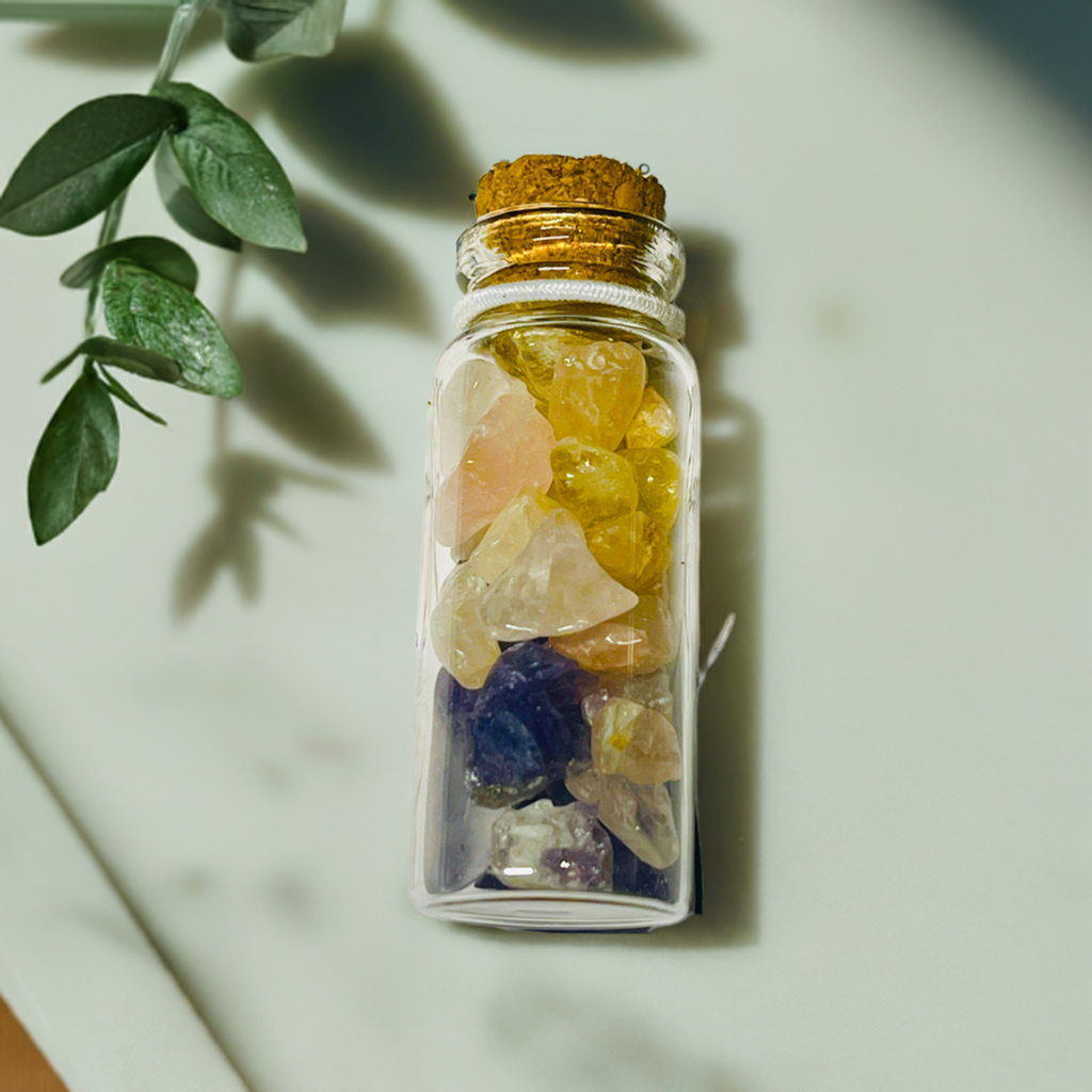 Crystal chips jar on a marble table with green leaves next to it