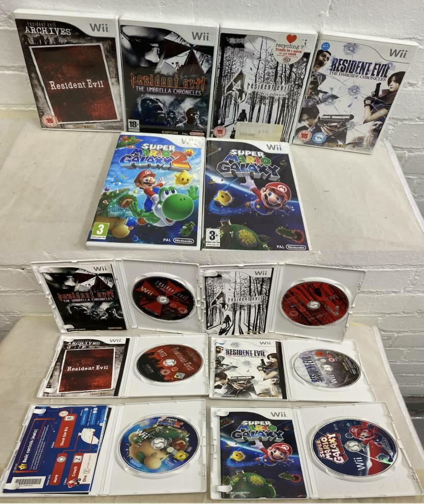 Six Nintendo Wii game cases opened to show Resident Evil and Mario Galaxy discs and manuals.