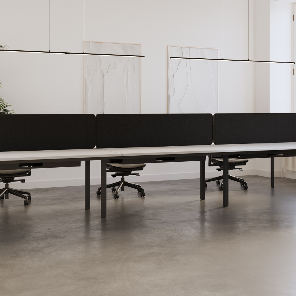 Firmo 6-person bench desk with tapered steel legs in an open-plan office