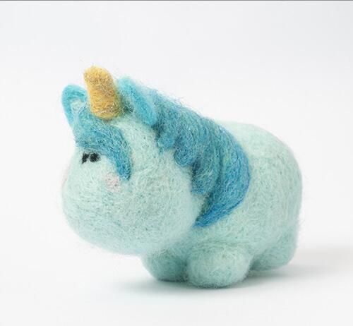 Cute needle-felted turquoise unicorn figurine with a yellow horn and blue mane, from a beginner felting kit.