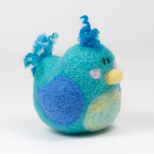 A 3D needle-felted blue bird named Birdie with a turquoise body, bright blue wings, a pale yellow tummy, and curly wool crest and tail.