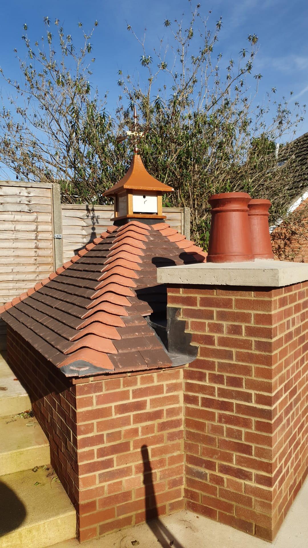 Full view of the brick dovecote man cave outbuilding with Victorian arrow weathervane on the hexagonal terracotta tiled turret roof
