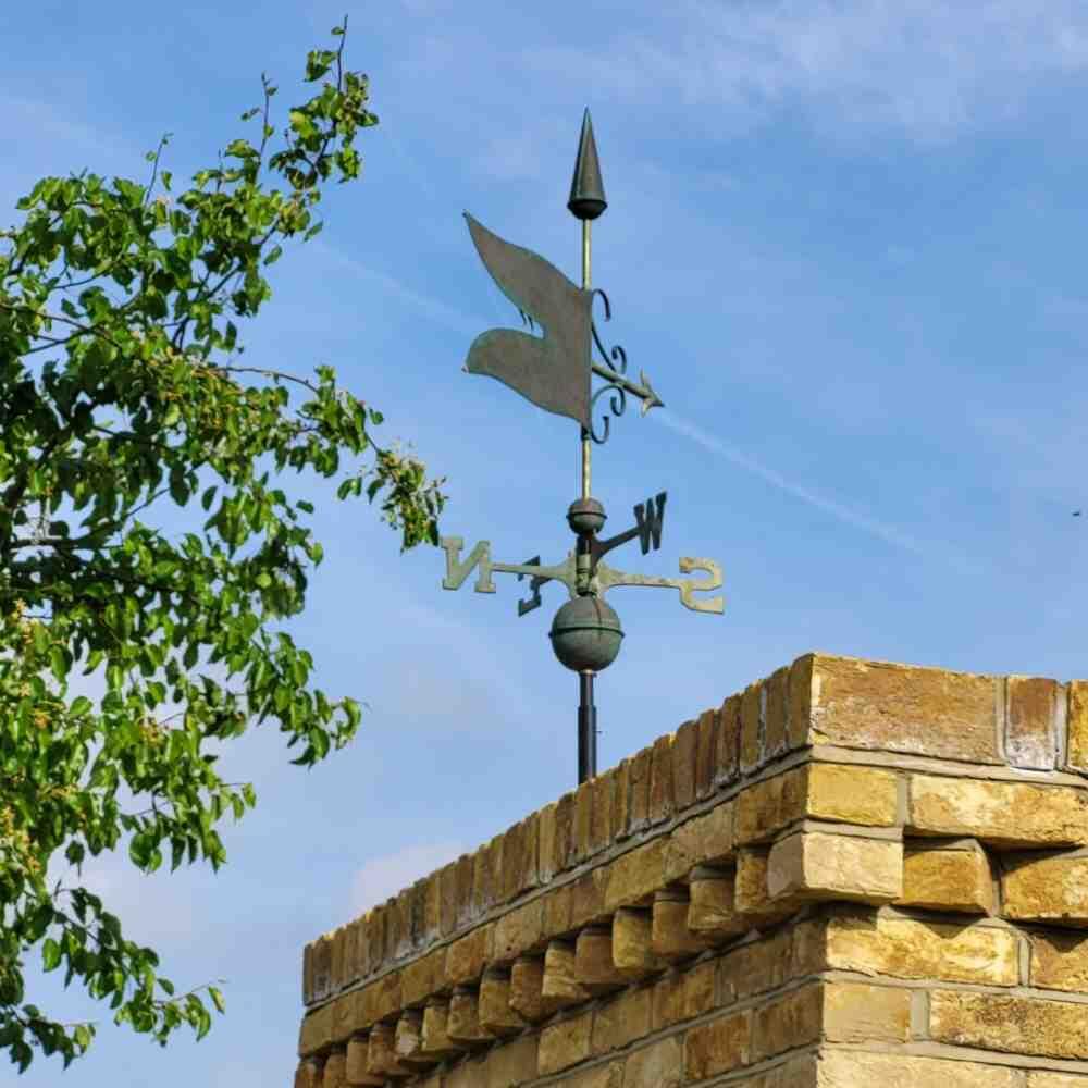 Copper verdigris banner weathervane fixed to yellow brick chimney stack using a 5 inch gable bracket