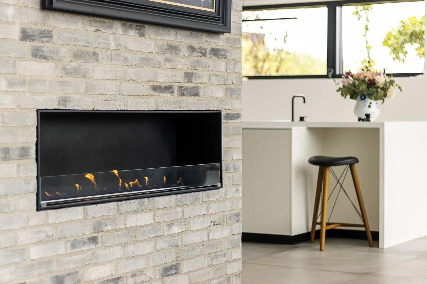 Montreal open-front bio-ethanol fire built into a pale brick wall beside a kitchen