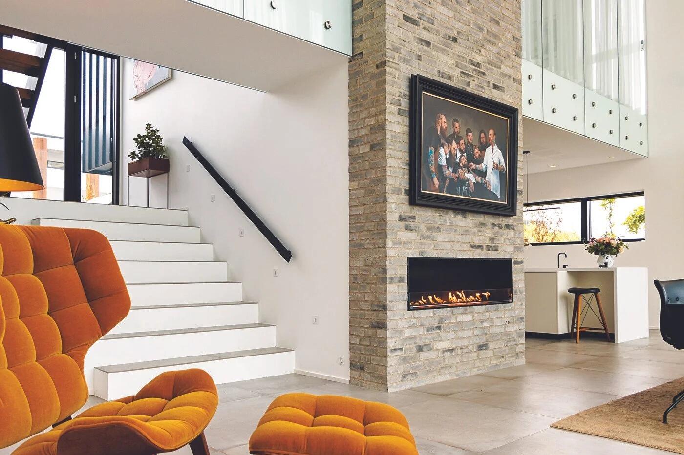 Montreal built-in fire in a double-height living room with orange lounge chairs