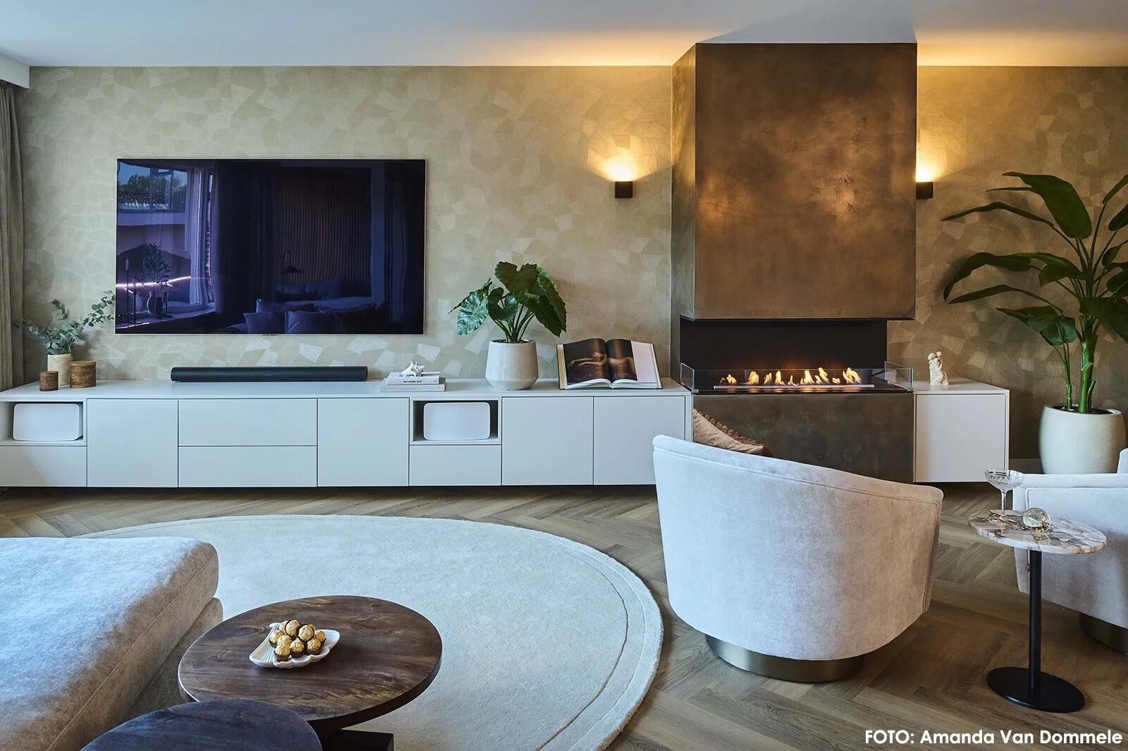 Wide view of a Montreal three-sided fire in a bronze feature wall beside a television
