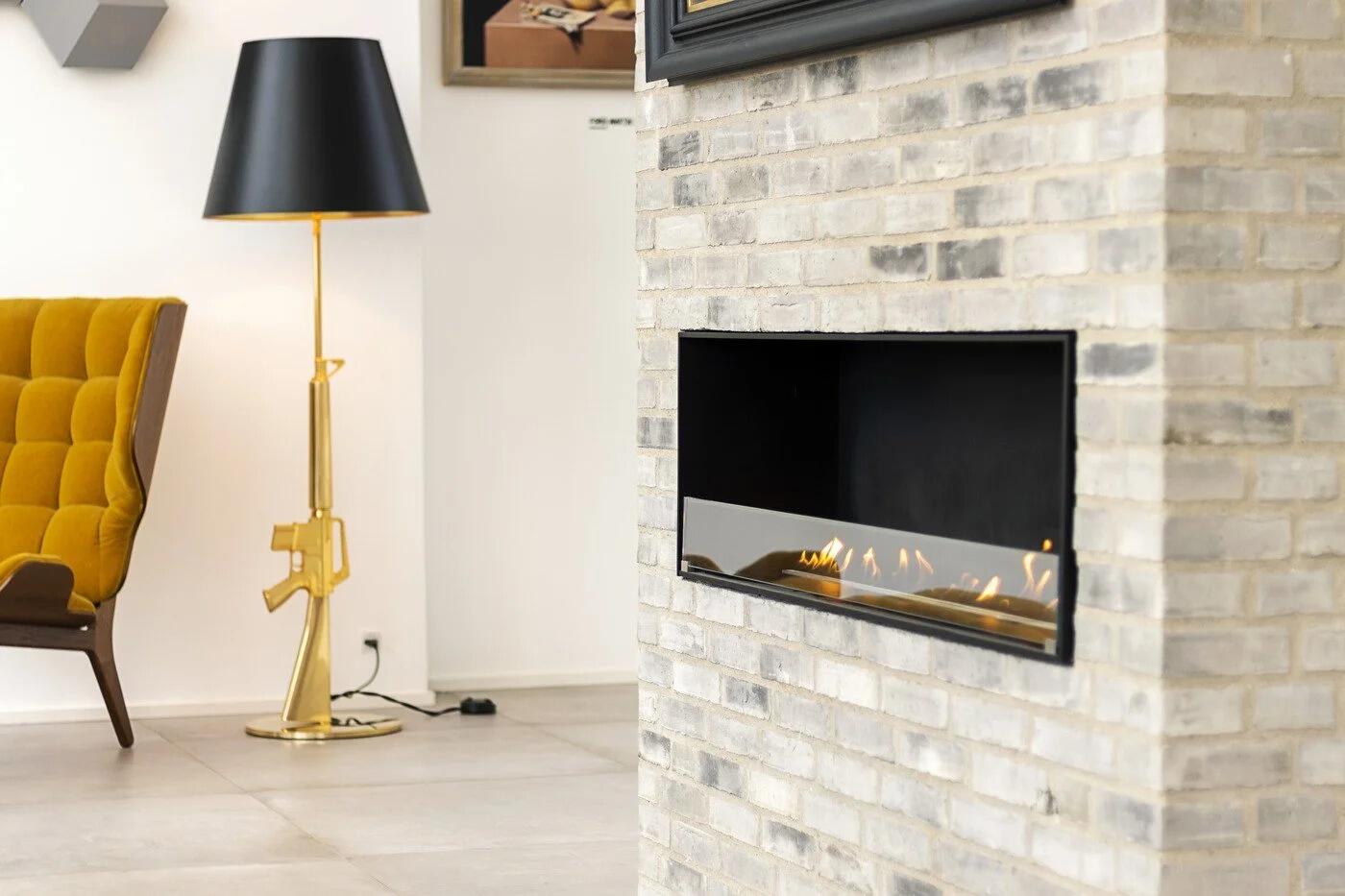 Montreal open-front fire in a brick wall beside a black floor lamp