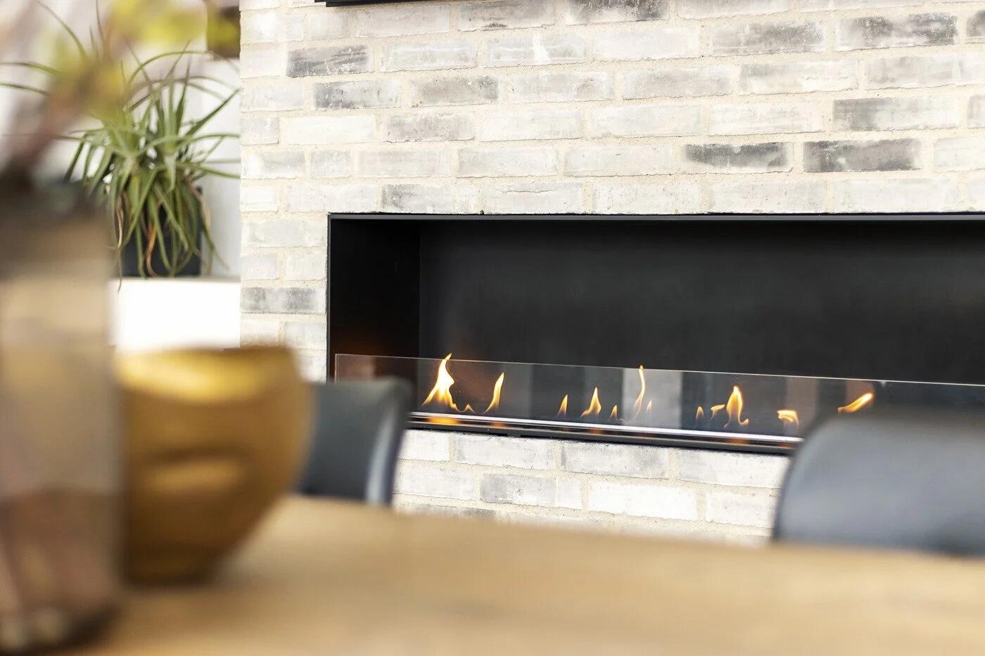 Montreal open-front fire seen past a dining table in a pale brick wall