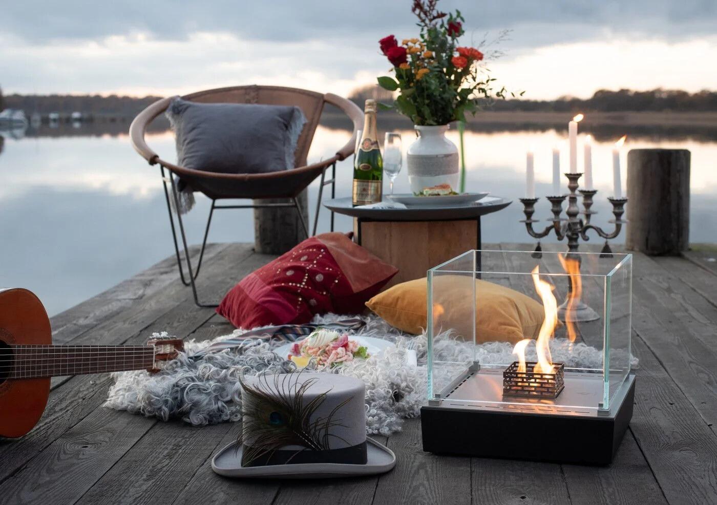 Nice table-top fire on a decking jetty with cushions and candles