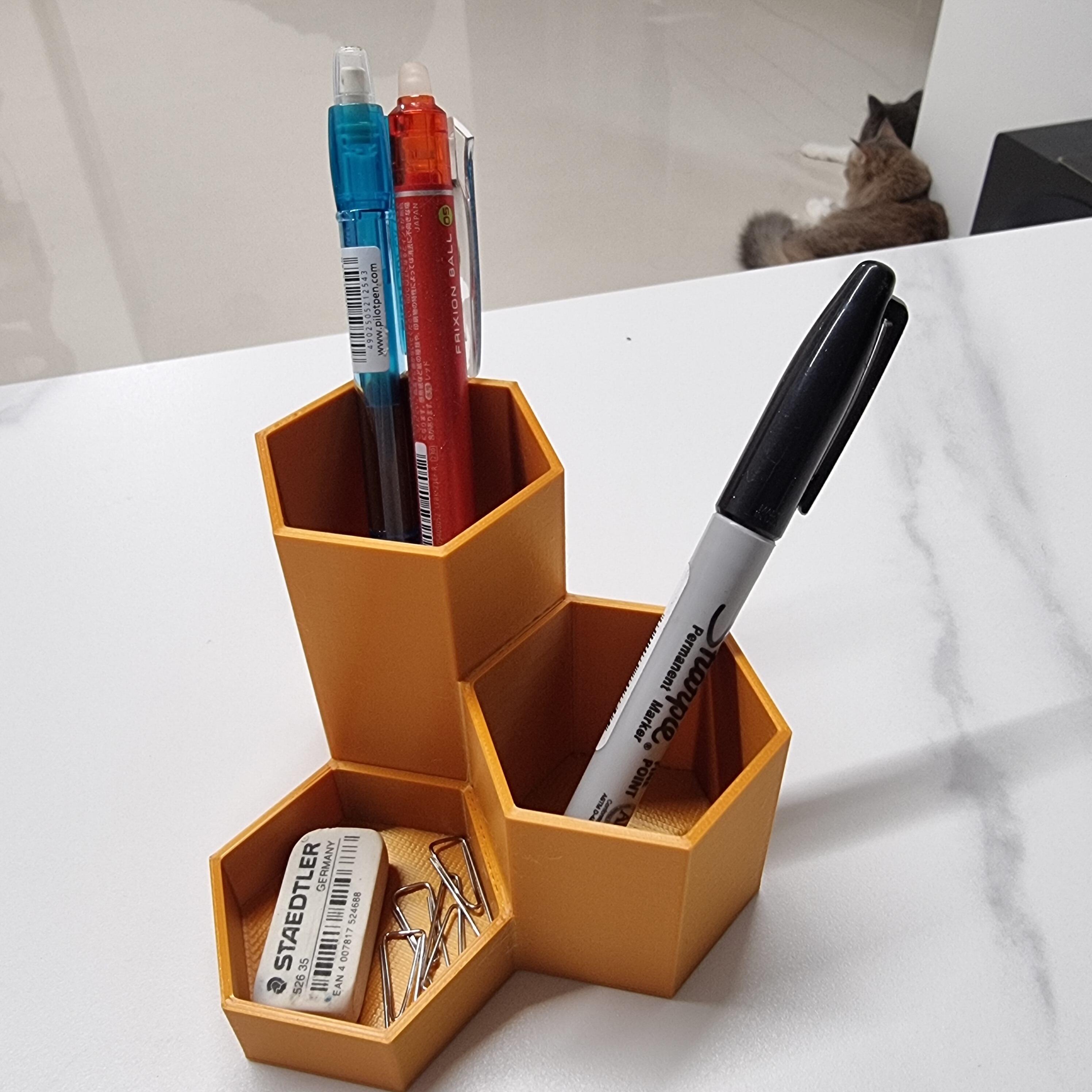 Orange honeycomb shape 3D printed desk pen pot with three levels of differing height hexagon containers filled with pens and other stationary