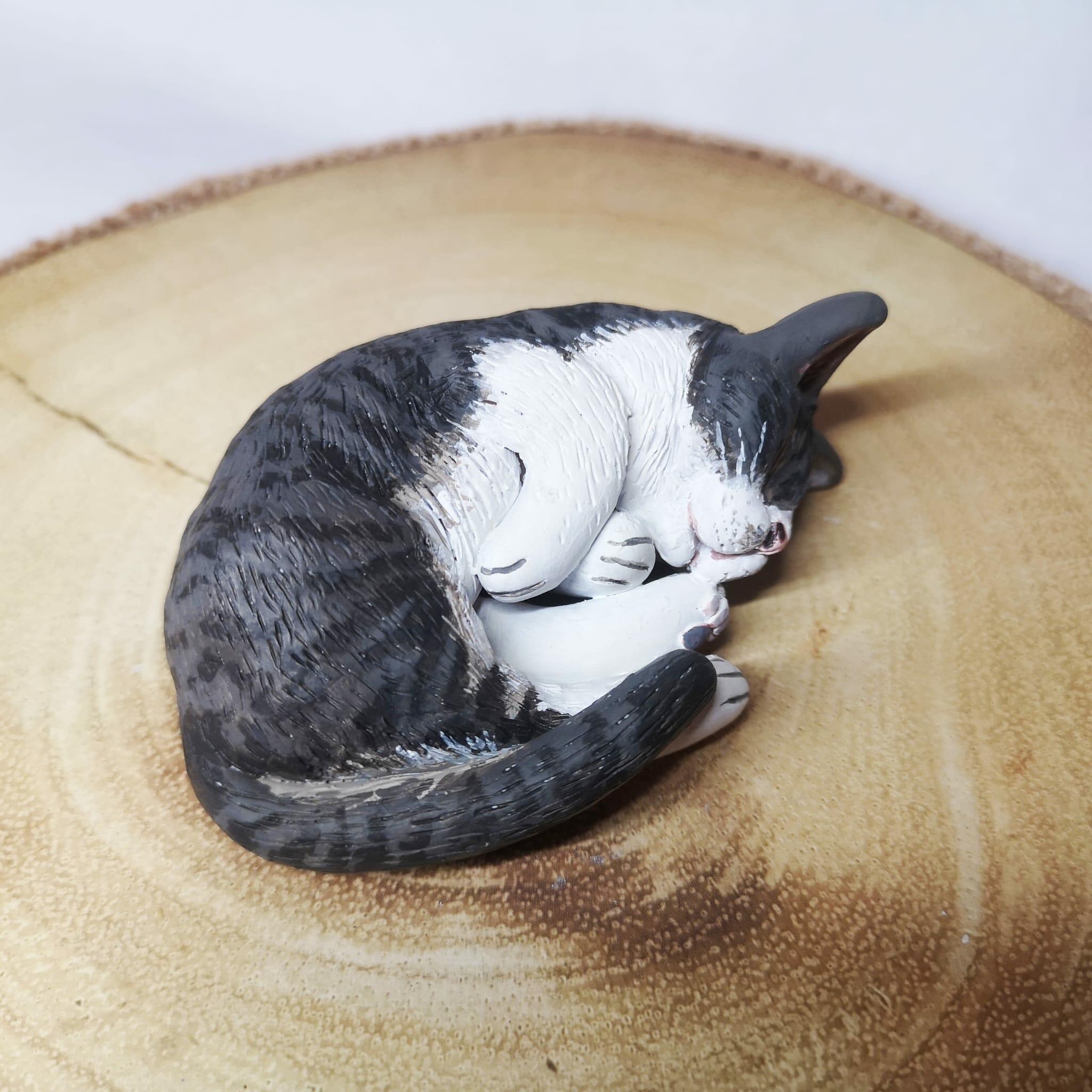 Handmade and handpainted clay model of a cat asleep, showcasing a lifelike representation of a cat in a natural sleeping position with eyes closed and body relaxed. Personalized and unique, this clay model captures the essence of a feline friend, conveying a sense of tranquility and contentment