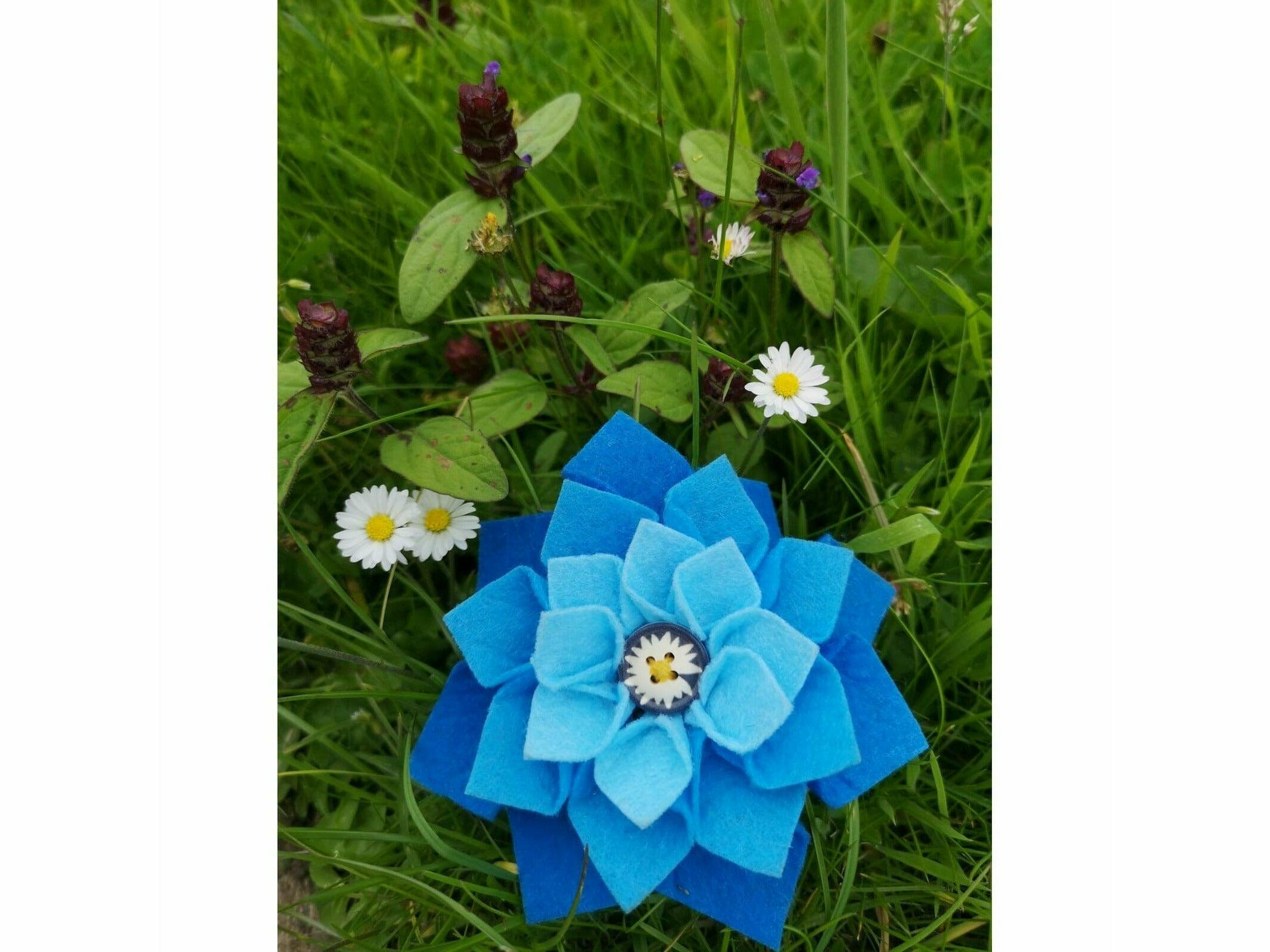 Stunning blue felt bridle charm on a bed of grass surrounded by daisy's