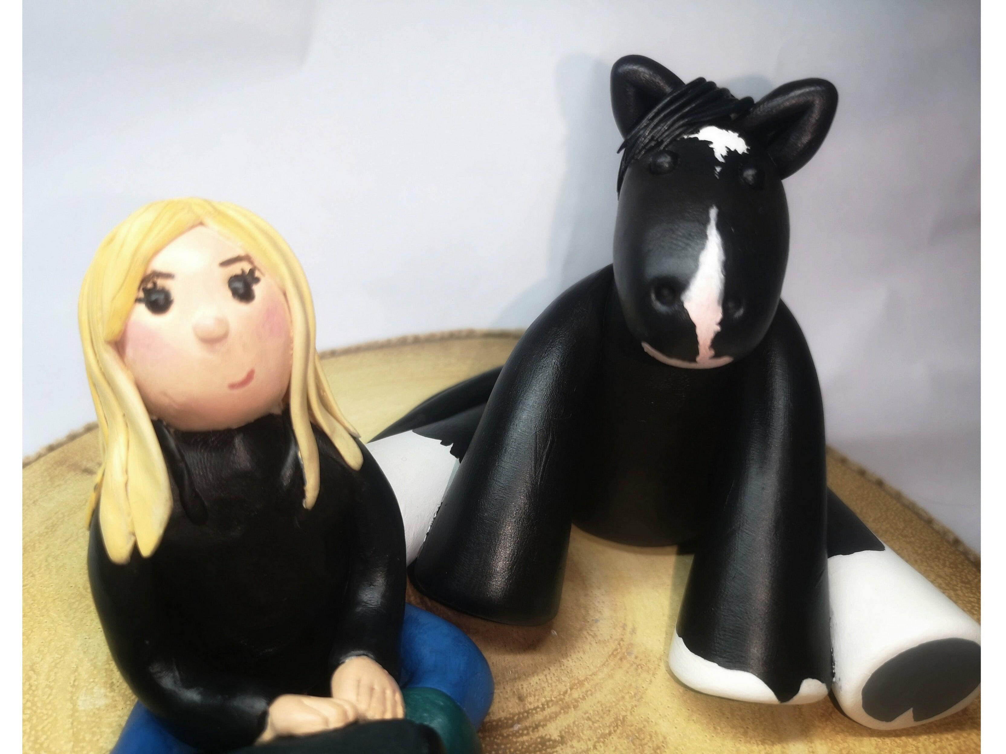A close up of a clay model featuring a blonde girl and a black horse