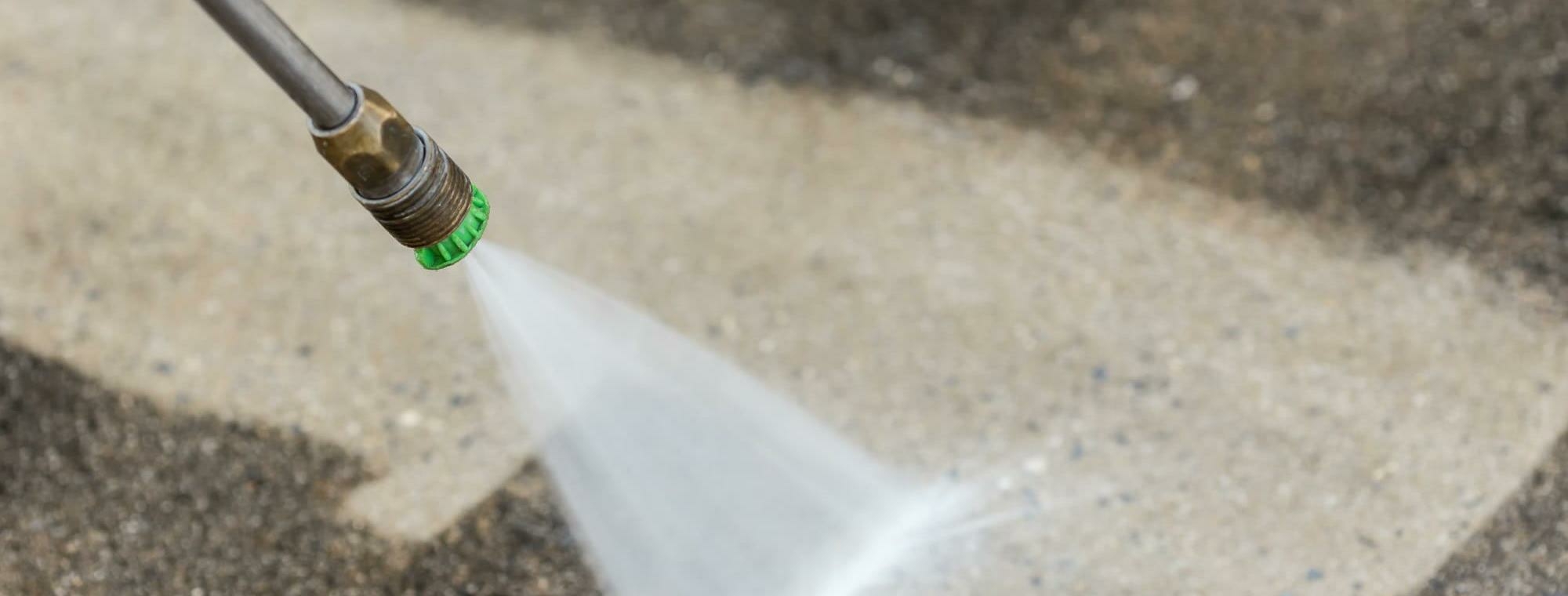 Pressure Washer Hose and Nozzle with a water jet cleaning an outdoor space