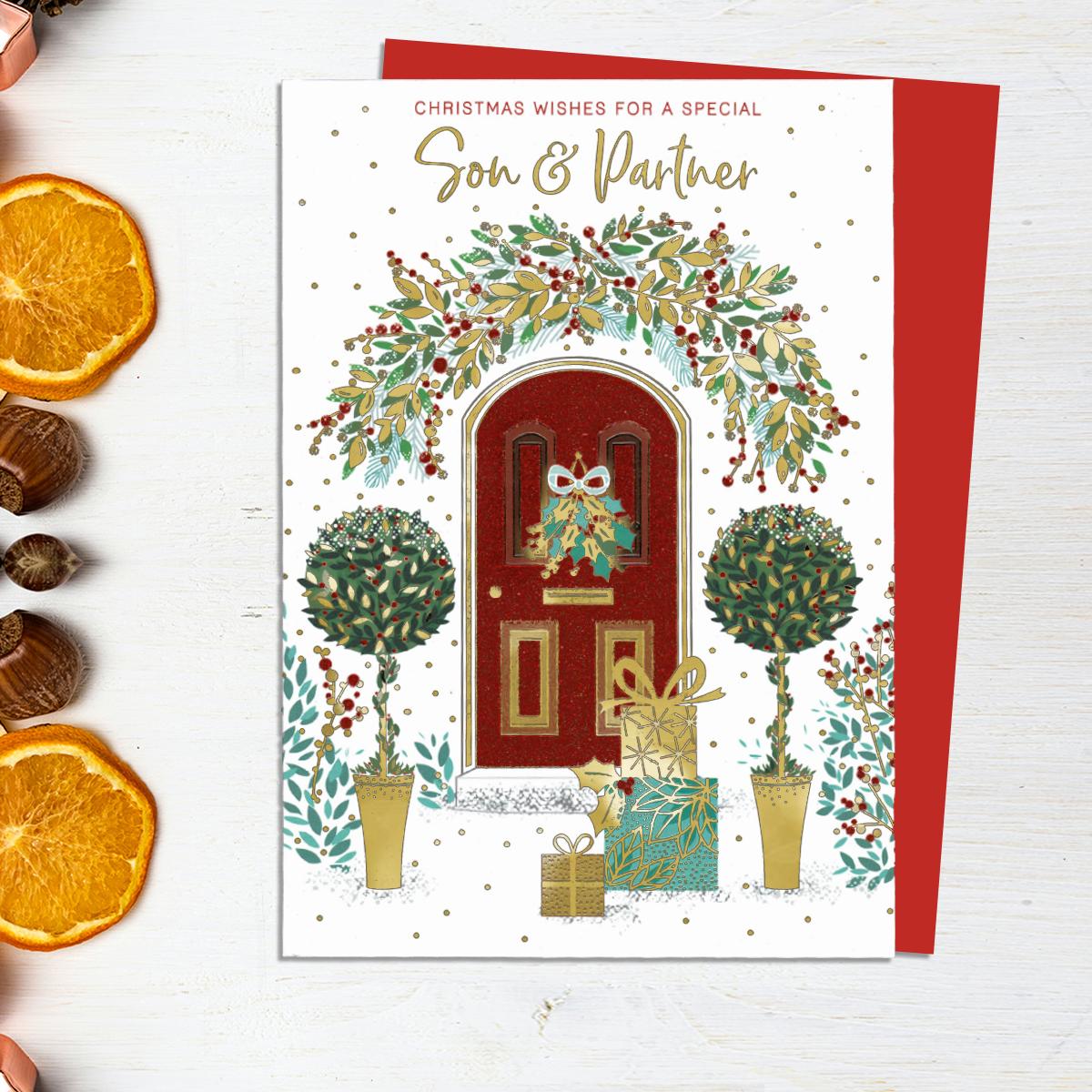 Christmas Wishes For A Special Son & Partner Showing A Beautifully Decorated Front Door With Garlands, Bay Trees And Gifts. Gold Foil  Lettering And Red Glitter Finishes This Card. Complete With Red Envelope
