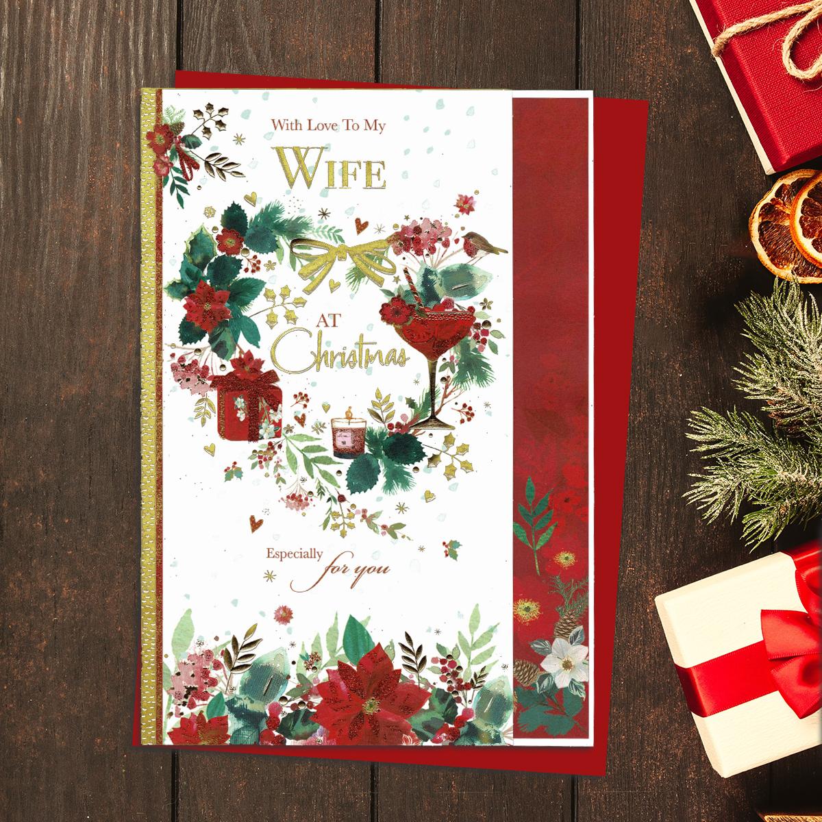 With Love To My Wife At Christmas Especially For You. Floral Christmas Wreath With Gifts ,Champagne Glass and Robin. Gold Foil Lettering And Red Glitter accents. Completed With A Co-Ordinating Red Envelope